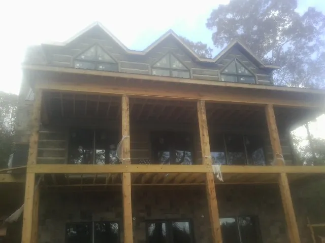 Dormers and porch framing on a large log home under construction — Roof Coating work by our crew in Double Springs