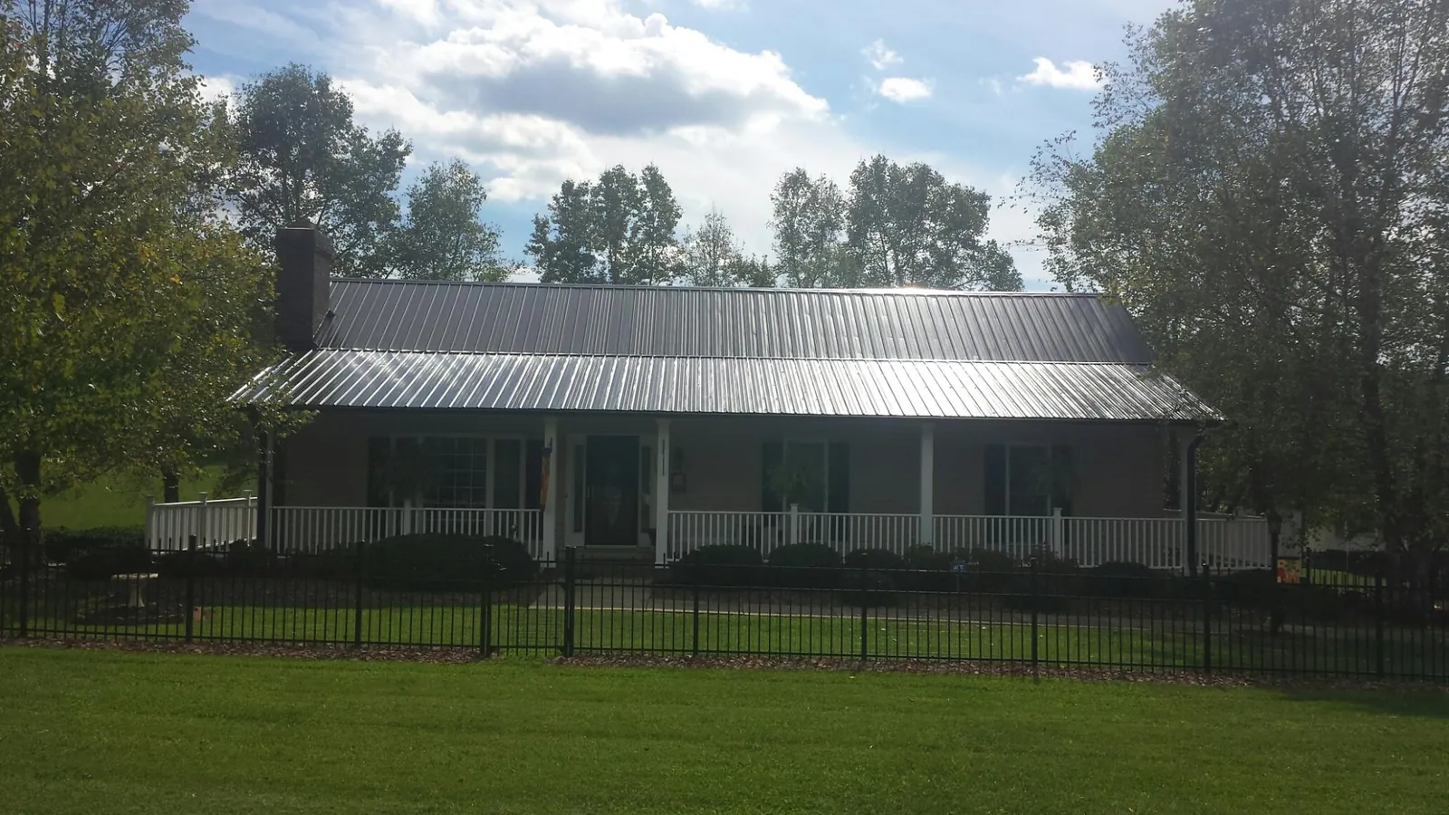 Gray metal roof on a brick ranch with a full width front porch — Gutter Guard Installation work by our crew in Double Springs