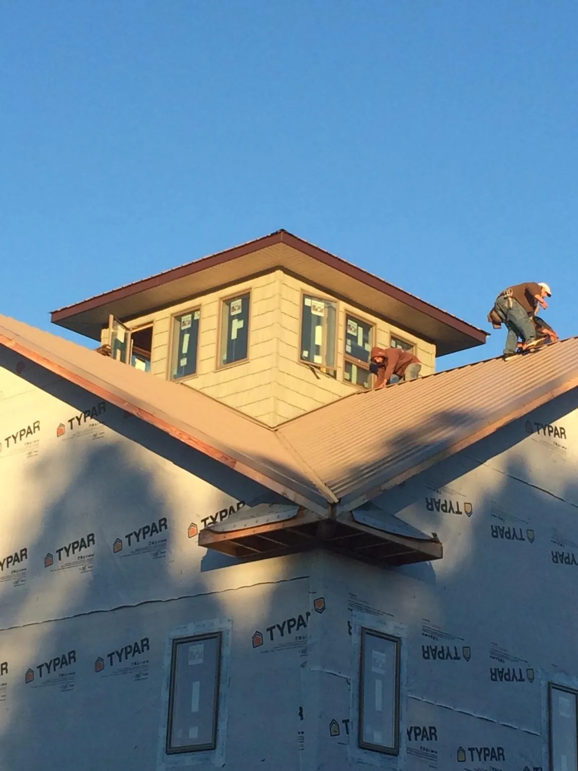 Roofers working around a rooftop cupola on a new metal roof at sunset — Roof Waterproofing in Double Springs by Roofing Brothers